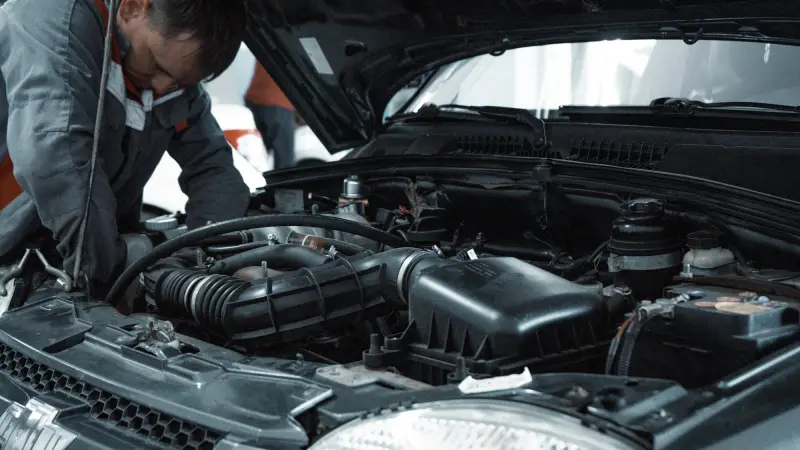 A technician inspecting the engine bay of a car
