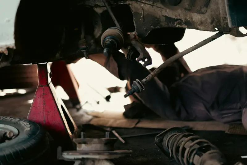 A technician working underneath a raised vehicle